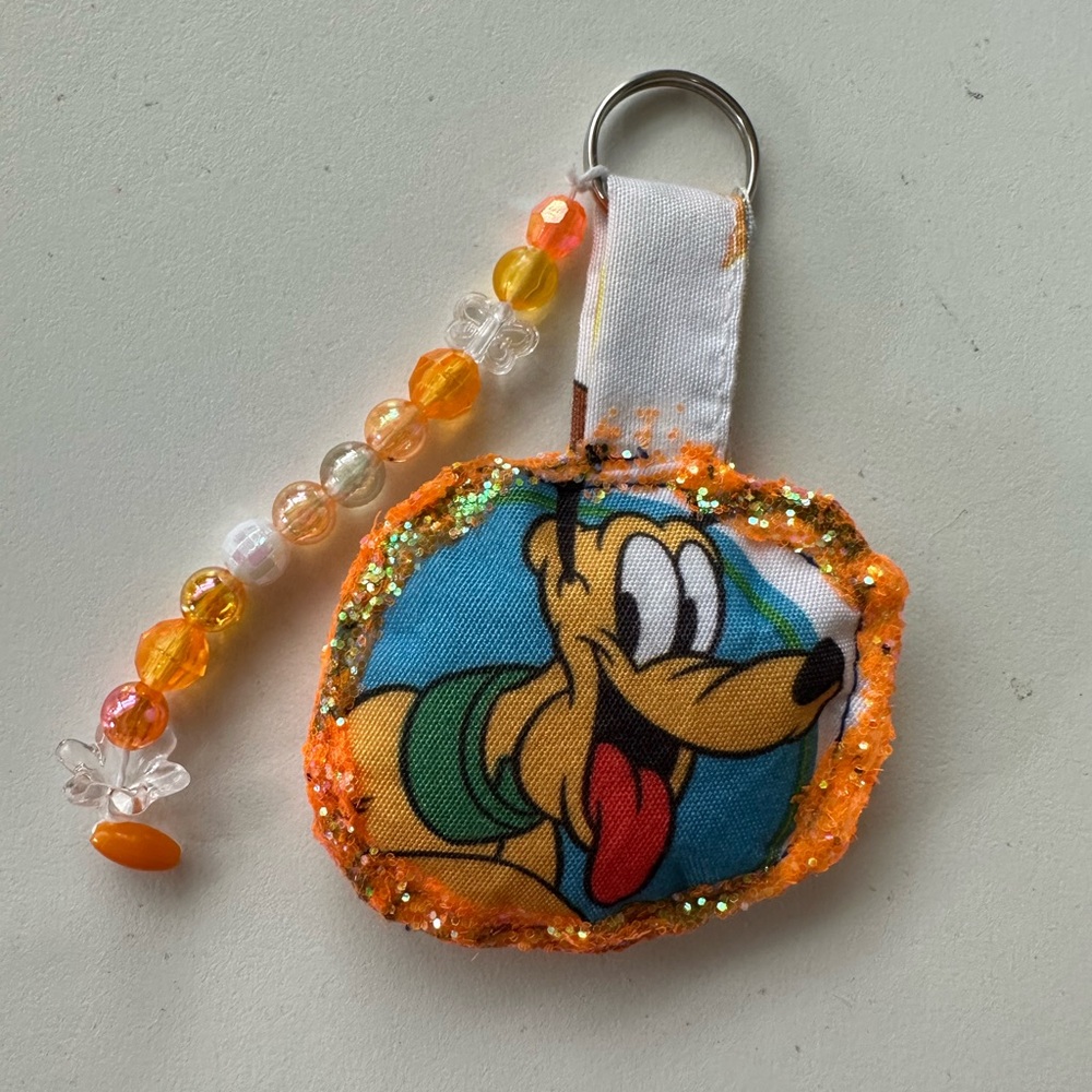 Bright orange Pluto 3” Bag Charm with removable Pluto hair clip